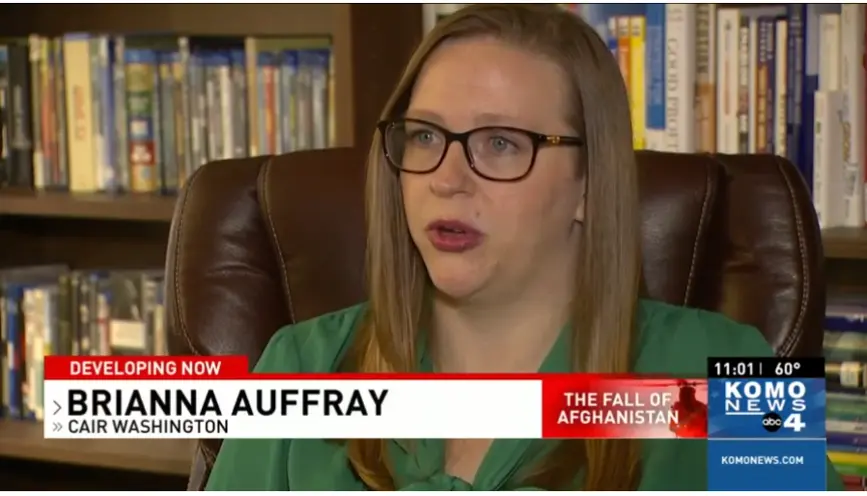 A photo of Brianna sitting against a bookshelf with a television news chyron that reads "Brianna Auffray, CAIR Washington: The Fall of Afghanistan. KOMO NEWS ABC 4"