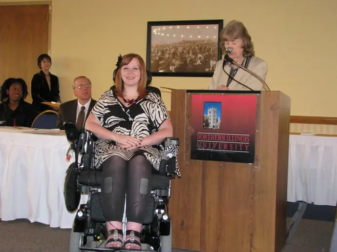 Brianna uses a wheelchair while accepting an award and diplomafrom Northern Illinois University.